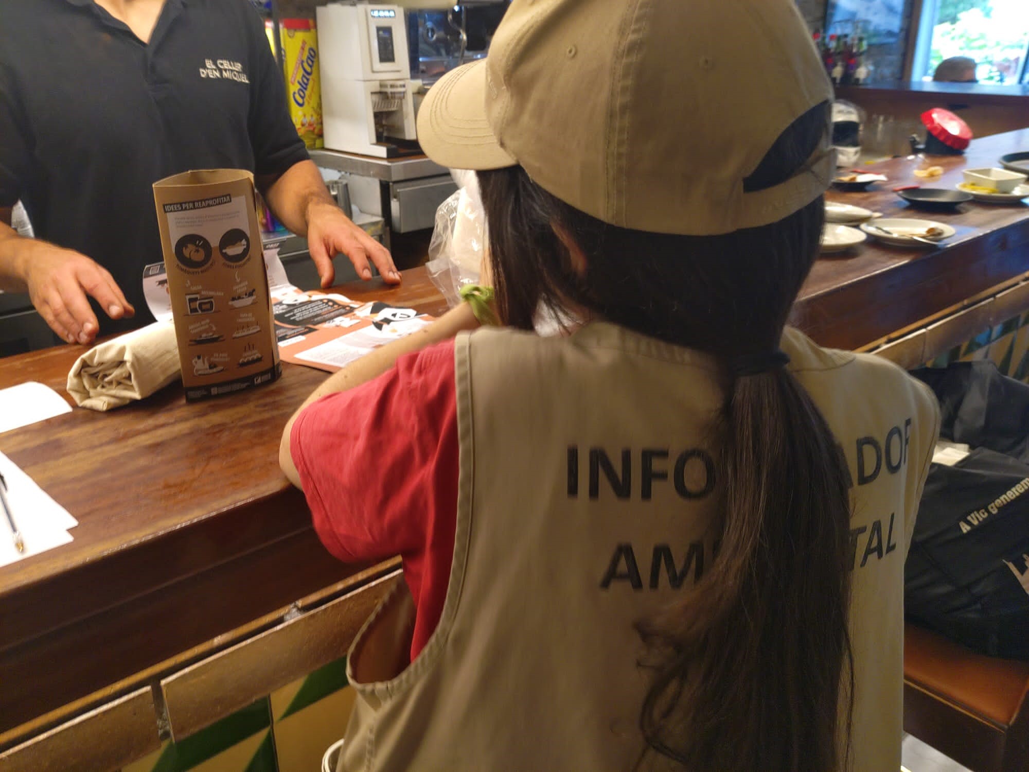 La informadora ambiental fent entrega del material al establiment adherit a la campanya